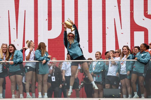 (FILES) England's captain Zoe Aldcroft holds the trophy as England players celebrate at a Red Roses Champions Party, held at Battersea Power Station in central London on September 28, 2025, after their win in the final of the Women’s Rugby World Cup against Canada the previous day. Aldcroft was made an Officer of the Order of the British Empire (OBE) in the 2026 New Year's Honours List. (Photo by HENRY NICHOLLS / AFP)