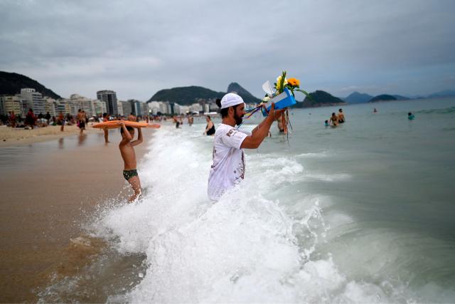 A worshipper pays tribute to Iemanja, the sea goddess of the Afro-Brazilian Umbanda religion, at Copacabana Beach in Rio de Janeiro, Brazil, on December 29, 2025. (Photo by MAURO PIMENTEL / AFP)