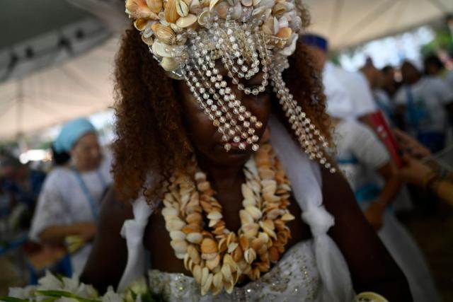 A worshipper pays tribute to Iemanja, the sea goddess of the Afro-Brazilian Umbanda religion, at Copacabana Beach in Rio de Janeiro, Brazil, on December 29, 2025. (Photo by MAURO PIMENTEL / AFP)