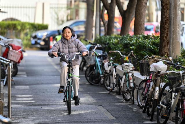 Estella, 14, a homeschooled student, rides her bicycle near her home in Shanghai on November 25, 2025. They are among a small number of parents in China who are rethinking the country's rigorous education system, in which school days can last 10 hours, with students often working late into the evening on extra tutoring and homework. (Photo by Hector RETAMAL / AFP) / TO GO WITH: China-education-children-family, FOCUS by Mary YANG