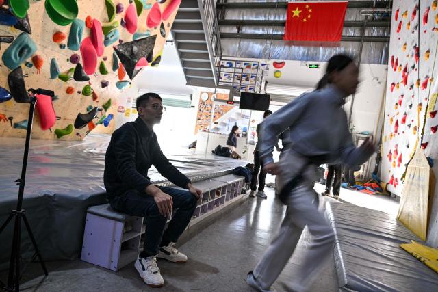 Estella (R), 14 years old, a homeschooled student, and her father Shen, take part in an indoor rock climbing in Shanghai on November 25, 2025. They are among a small number of parents in China who are rethinking the country's rigorous education system, in which school days can last 10 hours, with students often working late into the evening on extra tutoring and homework. (Photo by Hector RETAMAL / AFP) / TO GO WITH: China-education-children-family, FOCUS by Mary YANG