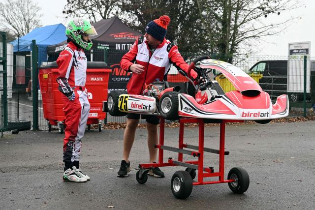 This photo taken on November 15, 2025 shows 15-year-old Skye Parker (L) with her kart during a day out at the Shenington Kart Racing Club track in Shenington, central England. A dozen girls whizzed around an English karting track, part of a pioneering drive to draw women into motorsports and maybe even race to the top in male-dominated Formula 1. (Photo by Paul ELLIS / AFP)