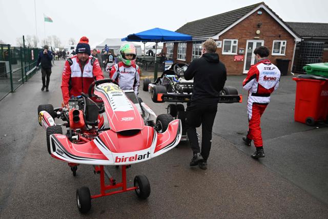 This photo taken on November 15, 2025 shows 15-year-old Skye Parker (2nd L) walking behind her kart during a day out at the Shenington Kart Racing Club track in Shenington, central England. A dozen girls whizzed around an English karting track, part of a pioneering drive to draw women into motorsports and maybe even race to the top in male-dominated Formula 1. (Photo by Paul ELLIS / AFP)
