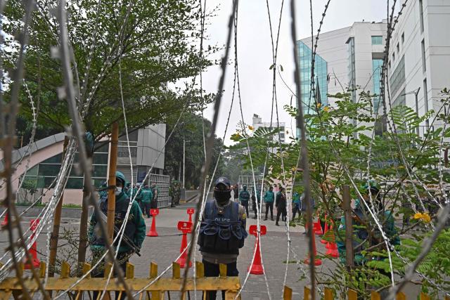 Police personnel stand guard behind barricades outside the Evercare hospital in Dhaka on December 30, 2025, after Bangladesh's former prime minister Khaleda Zia's death. Zia, who many believed would sweep elections next year to lead her country once again, died on December 30 aged 80, her Bangladesh Nationalist Party said. (Photo by Munir UZ ZAMAN / AFP)