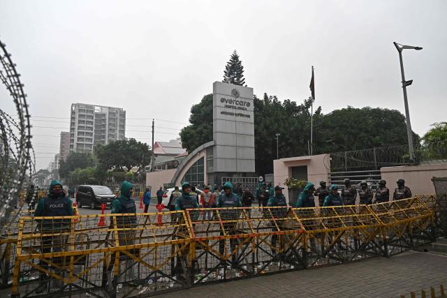 Police personnel stand guard behind barricades outside the Evercare hospital in Dhaka on December 30, 2025, after Bangladesh's former prime minister Khaleda Zia's death. Zia, who many believed would sweep elections next year to lead her country once again, died on December 30 aged 80, her Bangladesh Nationalist Party said. (Photo by Munir UZ ZAMAN / AFP)