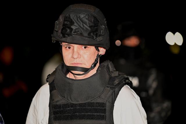 Roberto Alvarez, alias "El Gerente," an Ecuadorean alleged leader of a Colombian guerrilla group, is escorted upon landing at the Police base in Jose Joaquin de Olmedo International Airport in Guayaquil, Ecuador, on December 29, 2025, after being transferred from the United Arab Emirates. Alvarez, wanted by Ecuadorean authorities for the killing of 11 soldiers, has been identified by the government as the head of the Border Commands, a dissident faction of the now-defunct Colombian guerrilla group FARC that did not adhere to the 2016 peace agreement. (Photo by Marcos PIN / AFP)