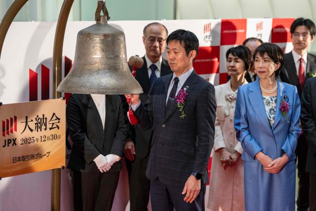 Hajime Moriyasu (C), head coach of Japan's national football team, hits the bell as he stands next to Japan’s Prime Minister Sanae Takaichi (R), to mark the closure of the end-of-year trading session at the Tokyo Stock Exchange (TSE) in Tokyo on December 30, 2025. (Photo by Yuichi YAMAZAKI / AFP)