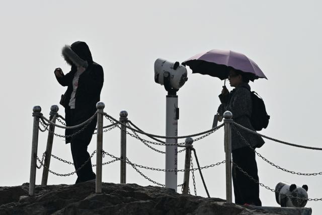 Visitors stand on a lookout point on Pingtan island, the closest point to Taiwan, in eastern China’s Fujian province on December 30, 2025. China's military drills around Taiwan entered their second day on December 30, the sixth major manoeuvres Beijing has held near the self-ruled island in recent years. (Photo by ADEK BERRY / AFP)