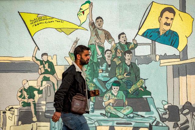 (FILES) A man walks past a mural depicting supporters of the Syrian Democratic Forces (SDF), one of them raising a flag showing the face of Abdullah Ocalan -- founding member of the militant Kurdistan Workers' Party (PKK) outlawed by Turkey, in Syria's northeastern city of Qamishli on December 16, 2024. Jailed Turkish Kurd leader Abdullah Ocalan said in a message published on December 30, 2025 that it was "crucial" for the Turkish government to broker a peace deal between the Kurdish-led Syrian Democratic Forces (SDF) and the Damascus government. (Photo by Delil SOULEIMAN / AFP)