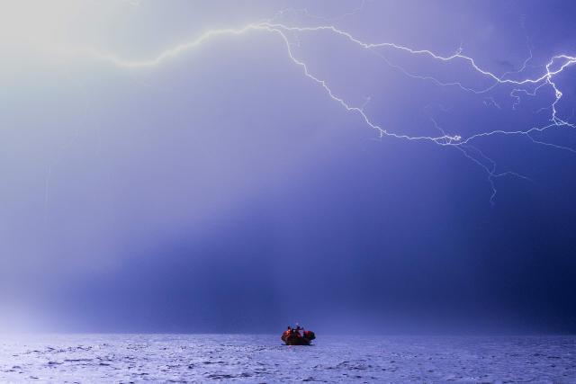 Lghtning strikes during a thunderstorm as crew members of the “Ocean Viking” rescue ship, operated by the French NGO SOS Mediterranee, take part in a team night exercise to prepare for a rescue situation at sea with a "RHIB", an inflatable dinghy, on their way to the search-and-rescue zone in international waters in the Mediterranean Sea, on December 29, 2025. Migrants rescue ship "Ocean Viking" is preparing to return to operations following the attack it suffered on August 24, 2025 when Libyan Coast Guard forces fired directly on the rescue vessel operated by the NGO SOS Mediterranee. (Photo by Sameer Al-DOUMY / AFP)