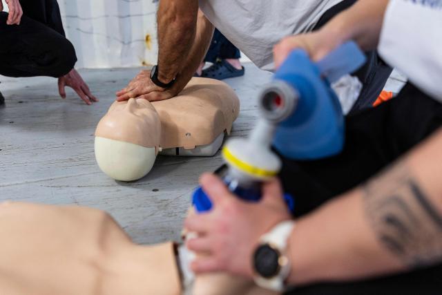 A crew member of the “Ocean Viking” rescue ship, operated by the French NGO SOS Mediterranee, performs a CPR as he takes part in a team exercise to prepare for a rescue situation at sea on the way to the search-and-rescue zone in international waters in the Mediterranean Sea, on December 27, 2025. Migrants rescue ship "Ocean Viking" is preparing to return to operations following the attack it suffered on August 24, 2025 when Libyan Coast Guard forces fired directly on the rescue vessel operated by the NGO SOS Mediterranee. (Photo by Sameer Al-DOUMY / AFP)