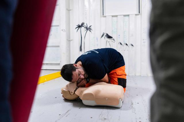 A crew member of the “Ocean Viking” rescue ship, operated by the French NGO SOS Mediterranee, performs a CPR as he takes part in a team exercise to prepare for a rescue situation at sea on the way to the search-and-rescue zone in international waters in the Mediterranean Sea, on December 27, 2025. Migrants rescue ship "Ocean Viking" is preparing to return to operations following the attack it suffered on August 24, 2025 when Libyan Coast Guard forces fired directly on the rescue vessel operated by the NGO SOS Mediterranee. (Photo by Sameer Al-DOUMY / AFP)
