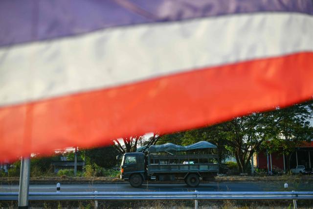 A Thai military vehicle passes by a Thai national flag in Kantharalak district in eastern Sisaket province on December 30, 2025, after weeks of deadly border clashes between Thailand and Cambodia. Thailand and Cambodia agreed to the "immediate" ceasefire on December 27, pledging to end renewed border clashes that killed dozens of people and displaced more than a million this month. But fresh allegation of violations from Bangkok and its threat to reconsider releasing Cambodian soldiers held by Thailand left a sustained truce in doubt, even as their foreign ministers wrapped up two days of talks hosted by China. (Photo by Amaury PAUL / AFP)