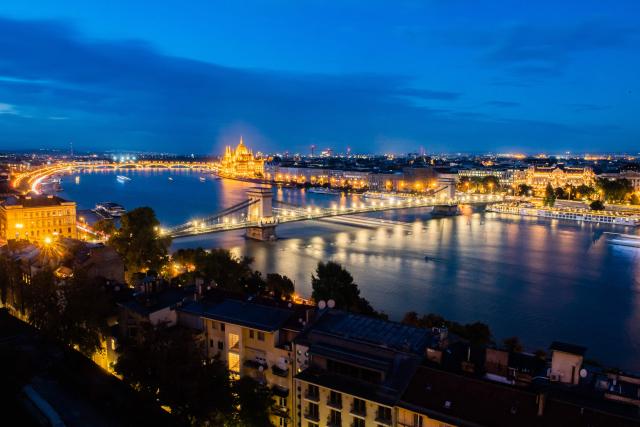(FILES) A general view shows the Danube River flowing past the illuminated Hungarian Parliament Building (top) in the Hungarian capital Budapest on September 16, 2024. Ratings agency Moody's downgraded the city of Budapest's credit rating to junk level late on December 30, 2025, pointing to weak liquidity and an increased default risk amid a row between Prime Minister Viktor Orban's nationalist government and the capital's opposition mayor. Moody's cut the city's credit rating from Baa3 to Ba1, a category with high risk often described as speculative or junk grade. (Photo by FERENC ISZA / AFP)