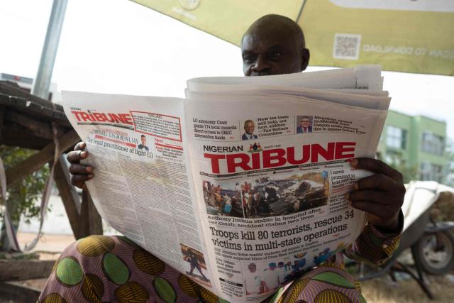 A residents reads a newspaper bearing headlines about a road accident involving British boxer Anthony Joshua, who was hospitalized in stable condition after a crash that killed two people, in Abeokuta on December 30, 2025. Former world heavyweight boxing champion Anthony Joshua was in a "stable condition" in hospital after a car accident in Nigeria that killed two close friends and associates, his promoter announced on December 29, 2025.
Matchroom confirmed police and media reports that he was involved in the smash, which happened on December 29, 2025 morning on a main road linking Lagos and Ibadan in the southwest of the country. (Photo by TOYIN ADEDOKUN / AFP)