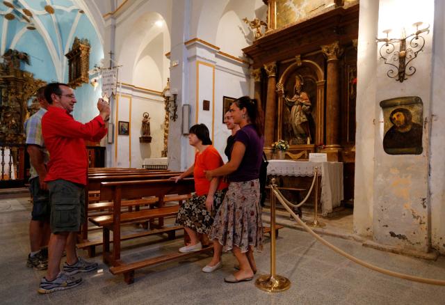 (FILES) People take pictures of the deteriorated version of "Ecce Homo" by 19th-century painter Elias Garcia Martinez, after its restoration by Cecilia Gimenez, 81, at the Borja Church in Zaragoza on August 28, 2012. Cecilia Gimenez, who became an unlikely global star in 2012 following the botched restoration of a portrait of Christ that sparked internet hilarity and drew crowds of curious visitors to her small town in northeast Spain, has died at the age of 94. (Photo by CESAR MANSO / AFP)
