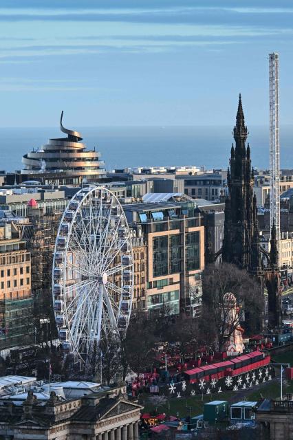 This general view shows some of the festive attractions on Princess Street in Edinburgh on December 30, 2025, ahead of the annual Hogmanay street party which culminates in a midnight fireworks display over the castle. An estimated 100,000 people from dozens of countries are expected in Edinburgh for the New Year events, the centrepiece of which is a street party and fireworks display on December 31. (Photo by Andy Buchanan / AFP)