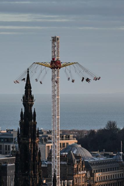 People take part in a carnival ride, just some of the festive attractions on Princess Street in Edinburgh on December 30, 2025, ahead of the annual Hogmanay street party which culminates in a midnight fireworks display over the castle. An estimated 100,000 people from dozens of countries are expected in Edinburgh for the New Year events, the centrepiece of which is a street party and fireworks display on December 31. (Photo by Andy Buchanan / AFP)