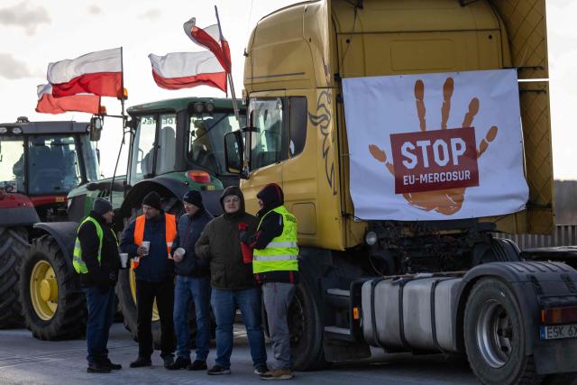 A group of farmers chat as they and other Polish farmers protest against the upcoming signing of a trade agreement between the European Union (EU) and the South American bloc Mercosur along the road next to the town of Wiskitki, on December 30, 2025. The EU-Mercosur pact would create the world's biggest free-trade area and help EU members export more vehicles, machinery, wines and spirits to Latin America at a time of global trade tensions. Farmers worry the Mercosur deal will see them undercut by a flow of cheaper goods from agricultural giant Brazil and its neighbours. (Photo by Wojtek RADWANSKI / AFP)