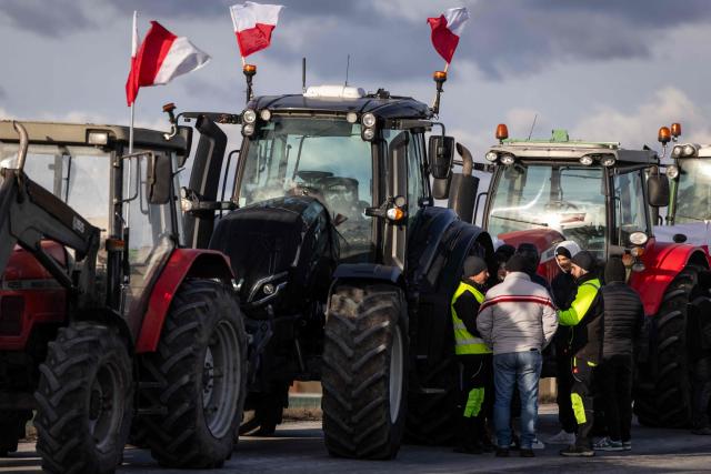 A group of farmers stands next to their tractors as they and other Polish farmers protest against the upcoming signing of a trade agreement between the European Union (EU) and the South American bloc Mercosur along the road next to the town of Wiskitki, on December 30, 2025. The EU-Mercosur pact would create the world's biggest free-trade area and help EU members export more vehicles, machinery, wines and spirits to Latin America at a time of global trade tensions. Farmers worry the Mercosur deal will see them undercut by a flow of cheaper goods from agricultural giant Brazil and its neighbours. (Photo by Wojtek RADWANSKI / AFP)