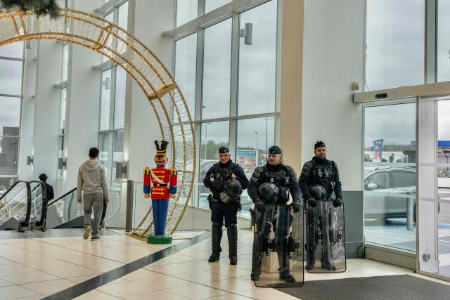 CRS riot police stand at the entrance of a supermarket during an action of several farmers unions to denounce the import of foreign products at a supermarket in Carcassonne, southern France, on December 30, 2025. French farmers have been fuming over a litany of issues, including a trade deal under negotiation between the European Union and South American bloc Mercosur, with any further decisions postponed to January. (Photo by Idriss Bigou-Gilles / AFP)