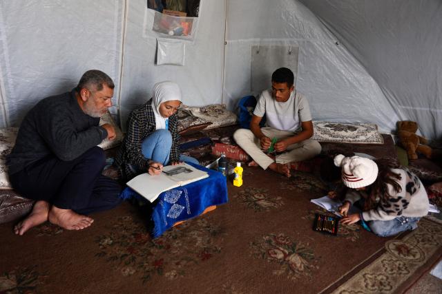 Fifteen-year-old displaced Palestinian Sarah Saada, who fled Beit Lahia in the northern Gaza Strip during Israeli bombardment, draws inside her tent as she sits with her family in Gaza City on December 30, 2025. Beginning in October, a fragile ceasefire has so far halted two years of war between Israel and Hamas in the Gaza Strip despite both sides trading accusations of truce violations. (Photo by Omar AL-QATTAA / AFP)