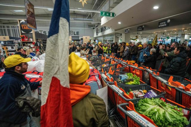 Members of the Confederation Rurale (CR) and Confederation paysanne farmers unions fill shopping carts with imported goods during an action to denounce the import of foreign products at a supermarket in Carcassonne, southern France, on December 30, 2025. French farmers have been fuming over a litany of issues, including a trade deal under negotiation between the European Union and South American bloc Mercosur, with any further decisions postponed to January. (Photo by Idriss Bigou-Gilles / AFP)