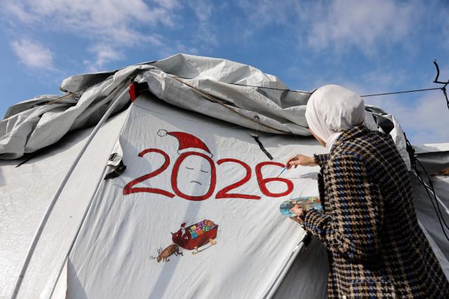 Fifteen-year-old displaced Palestinian Sarah Saada, who fled Beit Lahia in the northern Gaza Strip during Israeli bombardment, paints on her tent in Gaza City on December 30, 2025. Beginning in October, a fragile ceasefire has so far halted two years of war between Israel and Hamas in the Gaza Strip despite both sides trading accusations of truce violations. (Photo by Omar AL-QATTAA / AFP)