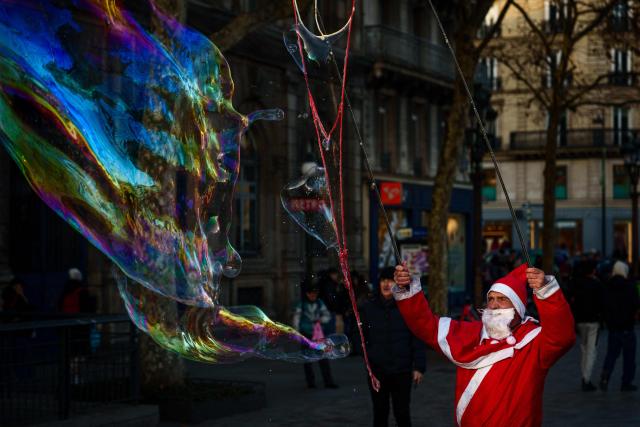 A street entertainer dressed as Father Christmas makes soap bubbles in central Paris on December 30, 2025. (Photo by Dimitar DILKOFF / AFP)