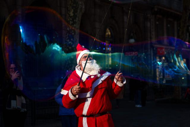 A street entertainer dressed as Father Christmas makes soap bubbles in central Paris on December 30, 2025. (Photo by Dimitar DILKOFF / AFP)