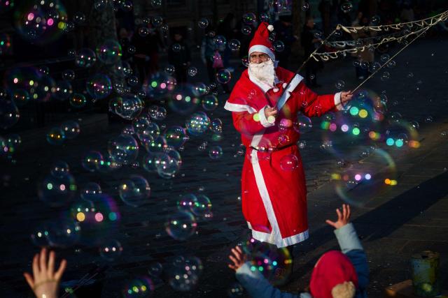 TOPSHOT - A street entertainer dressed as Father Christmas makes soap bubbles in central Paris on December 30, 2025. (Photo by Dimitar DILKOFF / AFP)
