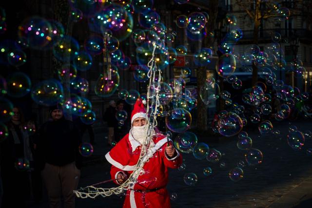 TOPSHOT - A street entertainer dressed as Father Christmas makes soap bubbles in central Paris on December 30, 2025. (Photo by Dimitar DILKOFF / AFP)