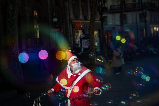 A street entertainer dressed as Father Christmas makes soap bubbles in central Paris on December 30, 2025. (Photo by Dimitar DILKOFF / AFP)