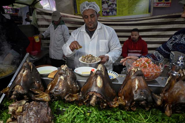 A Moroccan chef prepares a dish of lamb at an open air restaurant in the Jemaa el-Fna square in Marrakesh on December 30, 2025. (Photo by Khaled DESOUKI / AFP)