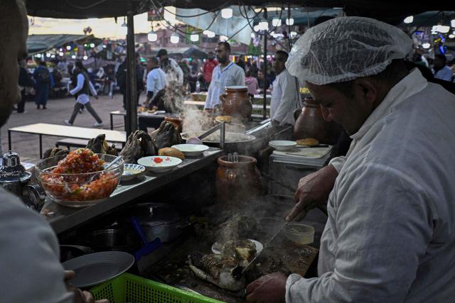 A Moroccan chef prepares a dish of lamb at an open air restaurant in the Jemaa el-Fna square in Marrakesh on December 30, 2025. (Photo by Khaled DESOUKI / AFP)