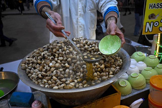 A Moroccan chef serves a snail dish for customers in the Jemaa el-Fna square in Marrakesh on December 30, 2025. (Photo by Khaled DESOUKI / AFP)