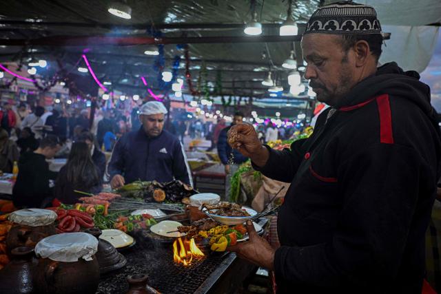 A Moroccan chef serves kebab for customers in the Jemaa el-Fnaa square in Marrakesh on December 30, 2025. (Photo by Khaled DESOUKI / AFP)