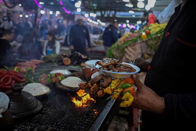 A Moroccan chef serves kebab for customers in the Jemaa el-Fnaa square in Marrakesh on December 30, 2025. (Photo by Khaled DESOUKI / AFP)