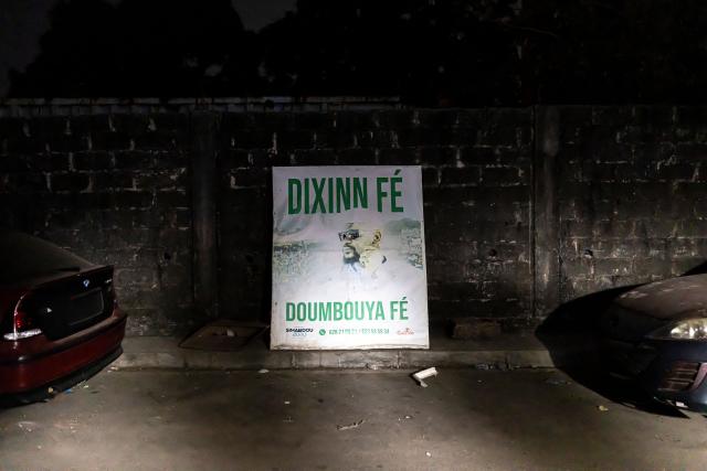A billboard depicting Guinea President Mamady Doumbouya is seen on an empty street after provisional results declared him the winner of Guinea’s presidential election in Conakry, on December 30, 2025. Guinea's junta chief Mamady Doumbouya, who had pledged not to run for office after seizing power four years ago, has been elected president after securing a sweeping majority of the vote, according to initial results by the country's election commission published on December 30. (Photo by PATRICK MEINHARDT / AFP)