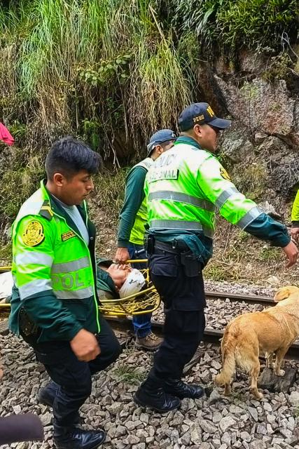 Police officers carry an injured passenger from one of the two trains affected after a head-on collision connecting Machu Picchu with Ollantaytambo in Pampacahua, Cusco Department, Peru, on December 30, 2025. On December 30, 2025, a head-on collision between two trains on the line that services Peru's Machu Picchu killed one person and injured at least 40 others, authorities said, updating an earlier toll. (Photo by Carolina Paucar / AFP)