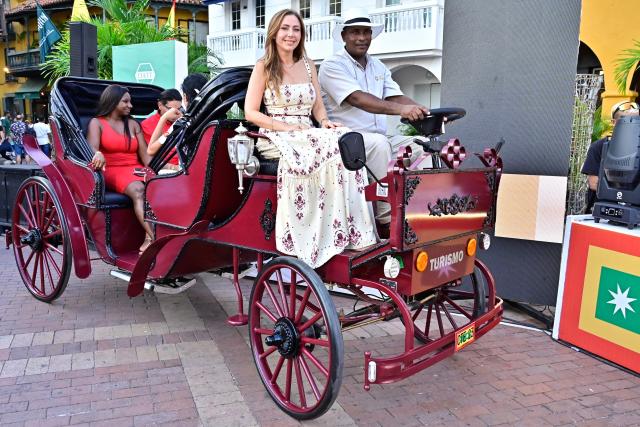 A coachman drives a new electric carriage as he transports tourists through the historic center of Cartagena, Colombia, on December 30, 2025. Traditional horse-drawn carriages will be banned starting December 29, 2025, in Cartagena, a tourist gem in Colombia, according to an announcement made by the local mayor on December 26. (Photo by Manuel PEDRAZA / AFP)