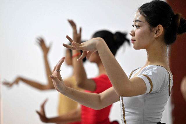 This photo taken on December 2, 2025 shows dance student Tola Thina (R), 18, practising with other students at the Secondary School of Fine Arts in Phnom Penh. Khmer classical dance, performed to traditional music, is renowned for its graceful hand gestures and stunning costumes and has a 1,000-year history. But after barely surviving Cambodia's genocidal Khmer Rouge regime in the 1970s, it is now under threat from a changing media and entertainment landscape, limited funding and economic challenges. (Photo by TANG CHHIN Sothy / AFP) / To go with 'CAMBODIA-CULTURE-EDUCATION-DANCE,FEATURE' by Suy SE