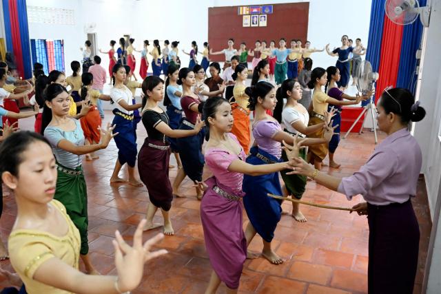This photo taken on December 2, 2025 shows a dance teacher (R) teaching students at the Secondary School of Fine Arts in Phnom Penh. Khmer classical dance, performed to traditional music, is renowned for its graceful hand gestures and stunning costumes and has a 1,000-year history. But after barely surviving Cambodia's genocidal Khmer Rouge regime in the 1970s, it is now under threat from a changing media and entertainment landscape, limited funding and economic challenges. (Photo by TANG CHHIN Sothy / AFP) / To go with 'CAMBODIA-CULTURE-EDUCATION-DANCE,FEATURE' by Suy SE