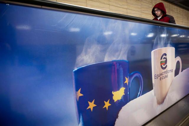 A commuter walks along a moving walkway in Sofia's subway beside an advertisement promoting Bulgaria's entry into the Eurozone on December 31, 2025, ahead of the country's adoption of the euro on January 1, 2026. (Photo by Nikolay DOYCHINOV / AFP)