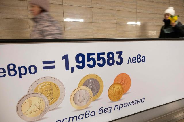 Commuters walk along a moving walkway in Sofia's subway beside an advertisement promoting Bulgaria's entry into the Eurozone on December 31, 2025, ahead of the country's adoption of the euro on January 1, 2026. (Photo by Nikolay DOYCHINOV / AFP)