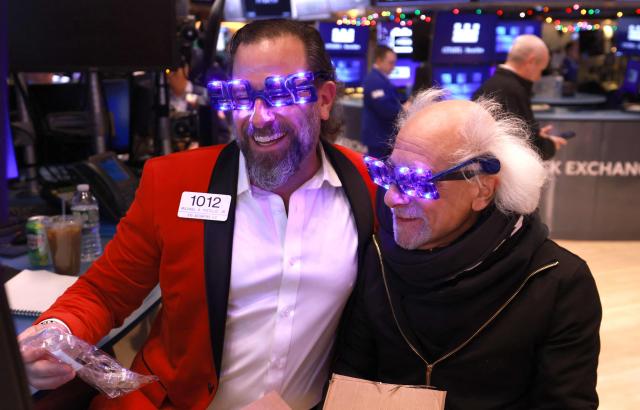 Trader Michael Pistillo and Peter Tuchman wear "2026" glasses as they work on the floor of the New York Stock Exchange (NYSE) at the opening bell in New York on December 31, 2025. (Photo by TIMOTHY A. CLARY / AFP)