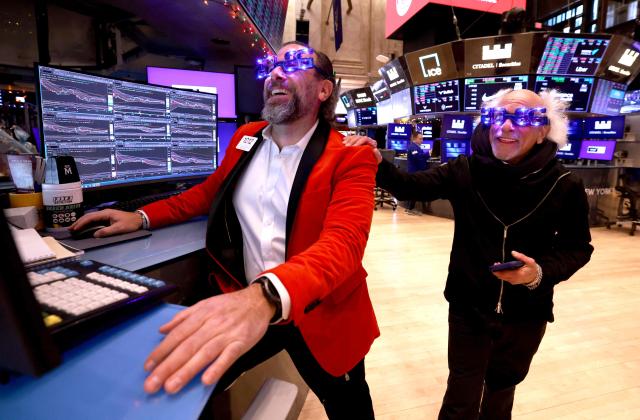Traders Michael Pistillo and Peter Tuchman wear "2026" glasses as they work on the floor of the New York Stock Exchange (NYSE) at the opening bell in New York on December 31, 2025. Wall Street's main indexes pulled back slightly on Wednesday, in a mild retreat that still sets the stage for a robust showing for all of 2025. (Photo by TIMOTHY A. CLARY / AFP)