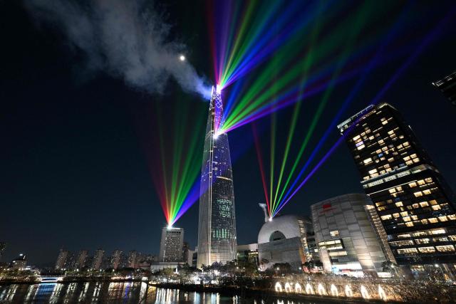 TOPSHOT - Laser lights illuminate the midnight sky over the Lotte World Tower, South Korea's tallest building in Seoul during New Year’s Day celebrations on January 1, 2026. (Photo by Jung Yeon-je / AFP)