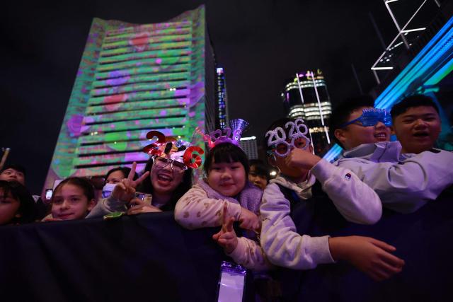 Revellers pose for a photograph during the New Year’s countdown celebrations in Central, Hong Kong, on December 31, 2025. (Photo by May JAMES / AFP)