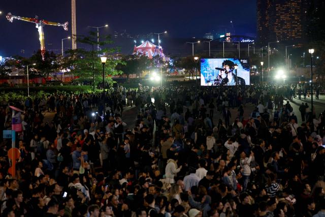 Revellers watch a performance in a big screen during Hong Kong's countdown celebrations in Central, Hong Kong, on December 31, 2025. (Photo by May JAMES / AFP)